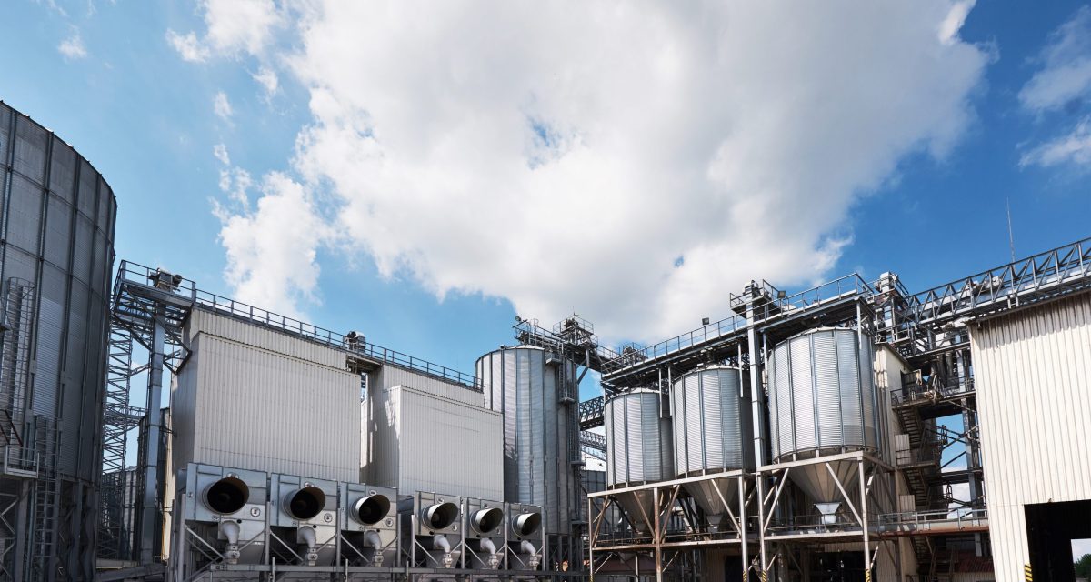 Agricultural Silos. Building Exterior. Storage and drying of grains, wheat, corn, soy, sunflower against the blue sky with white clouds.